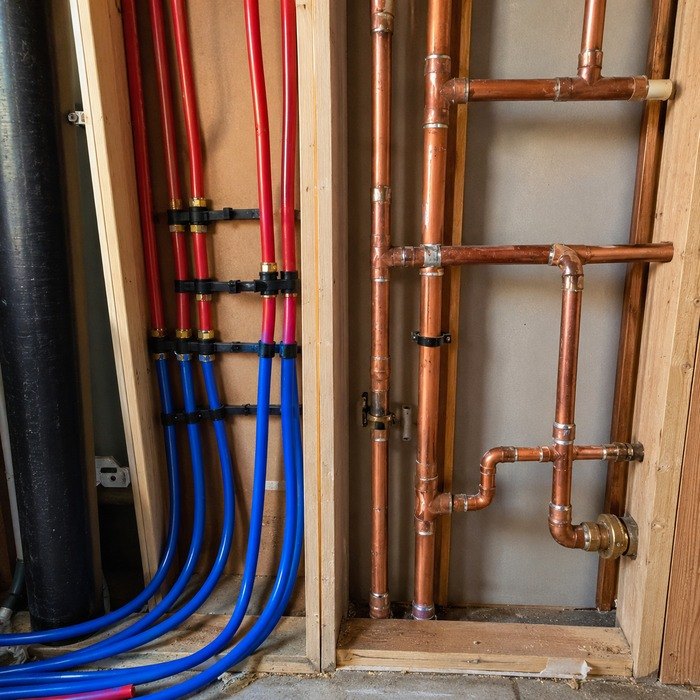 Copper and PEX supply piping side by side inside a wall