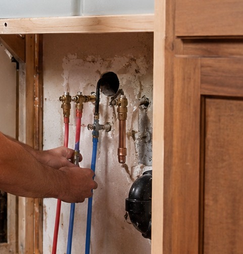 New red and blue PEX supply lines under a sink cabinet